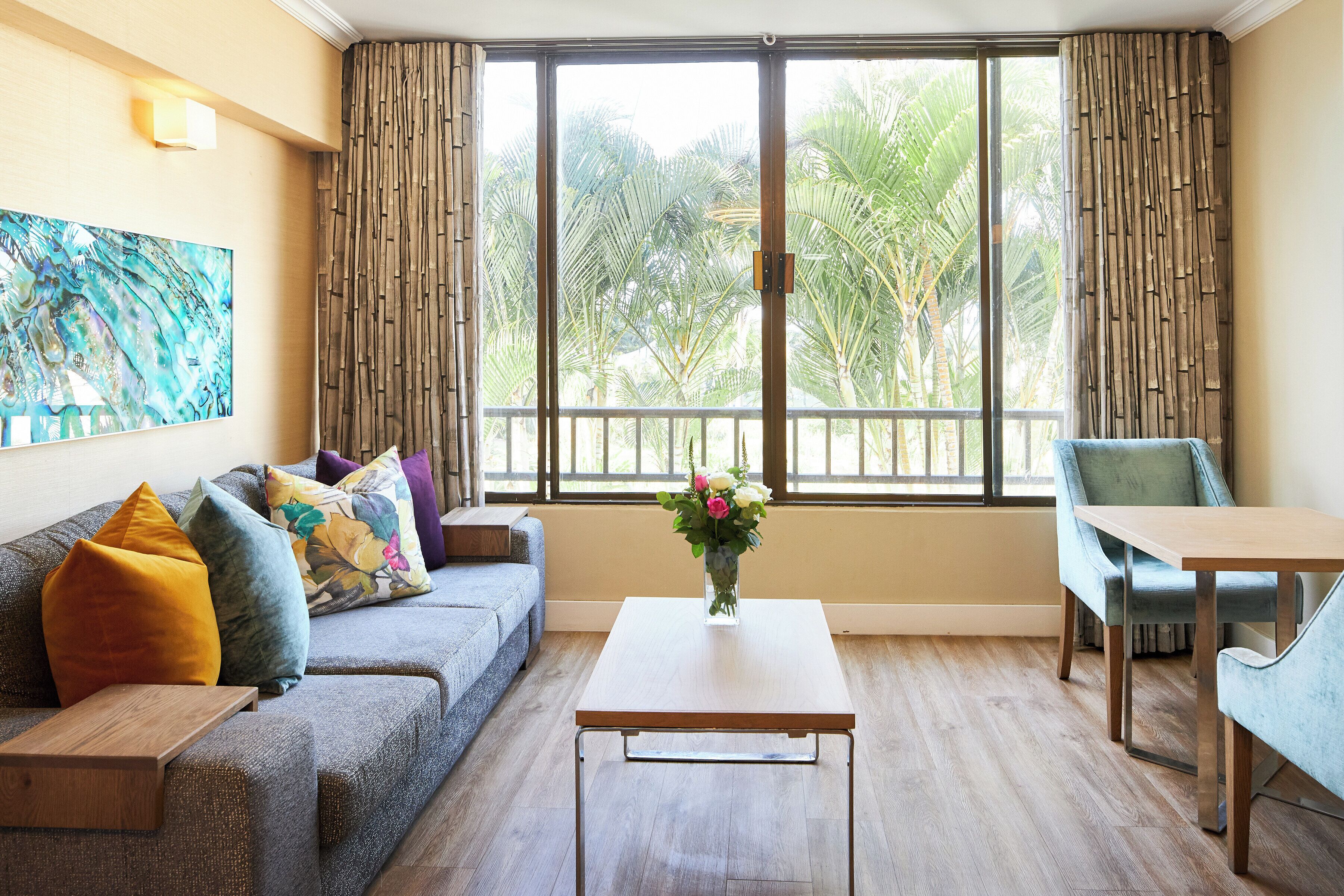 A room with a sofa, a dining table, and a window with curtains.
