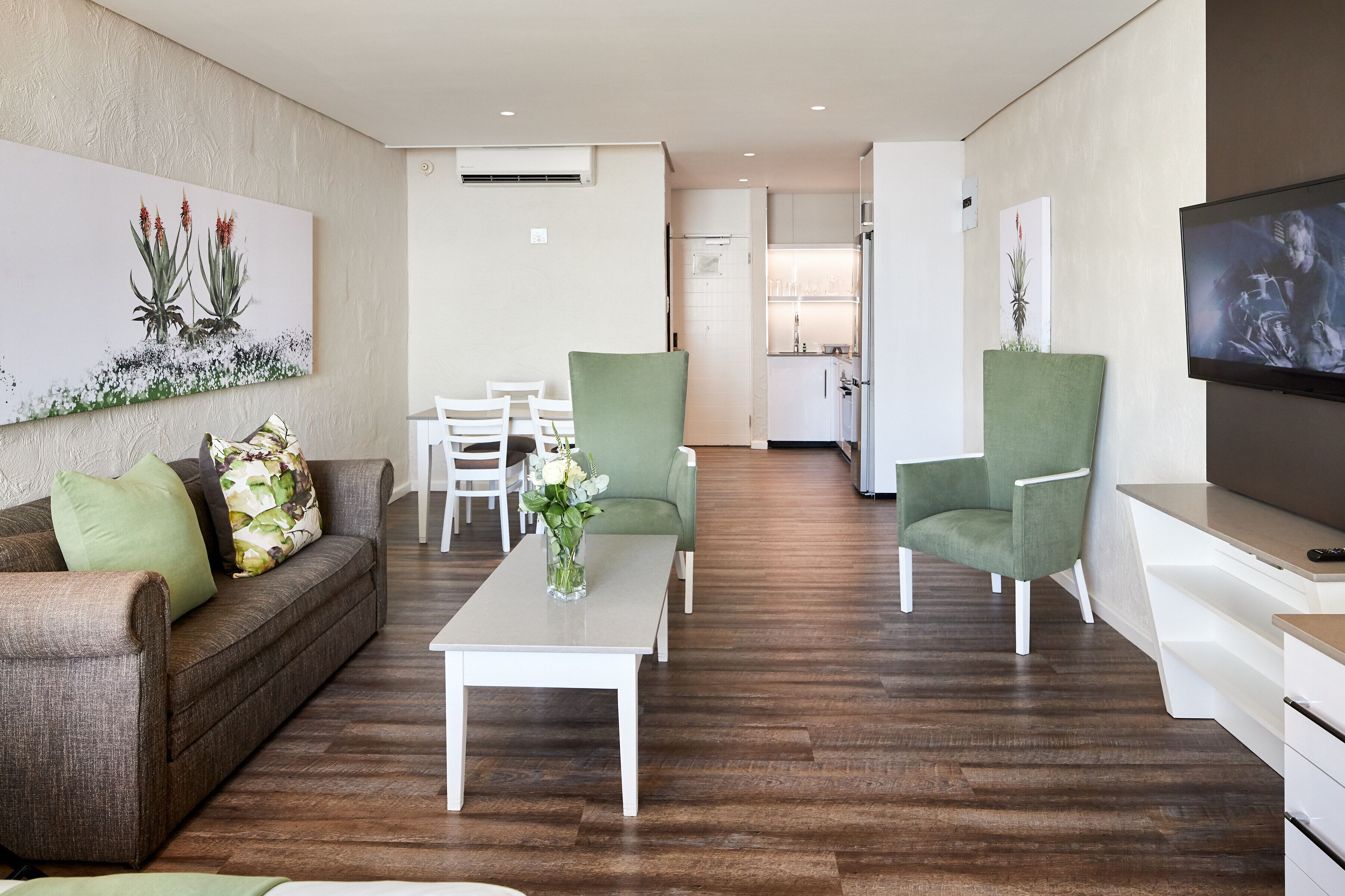 A modern living room with a sofa, chairs, a coffee table, and a TV.