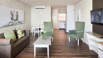 A modern living room with a sofa, chairs, a coffee table, and a TV.