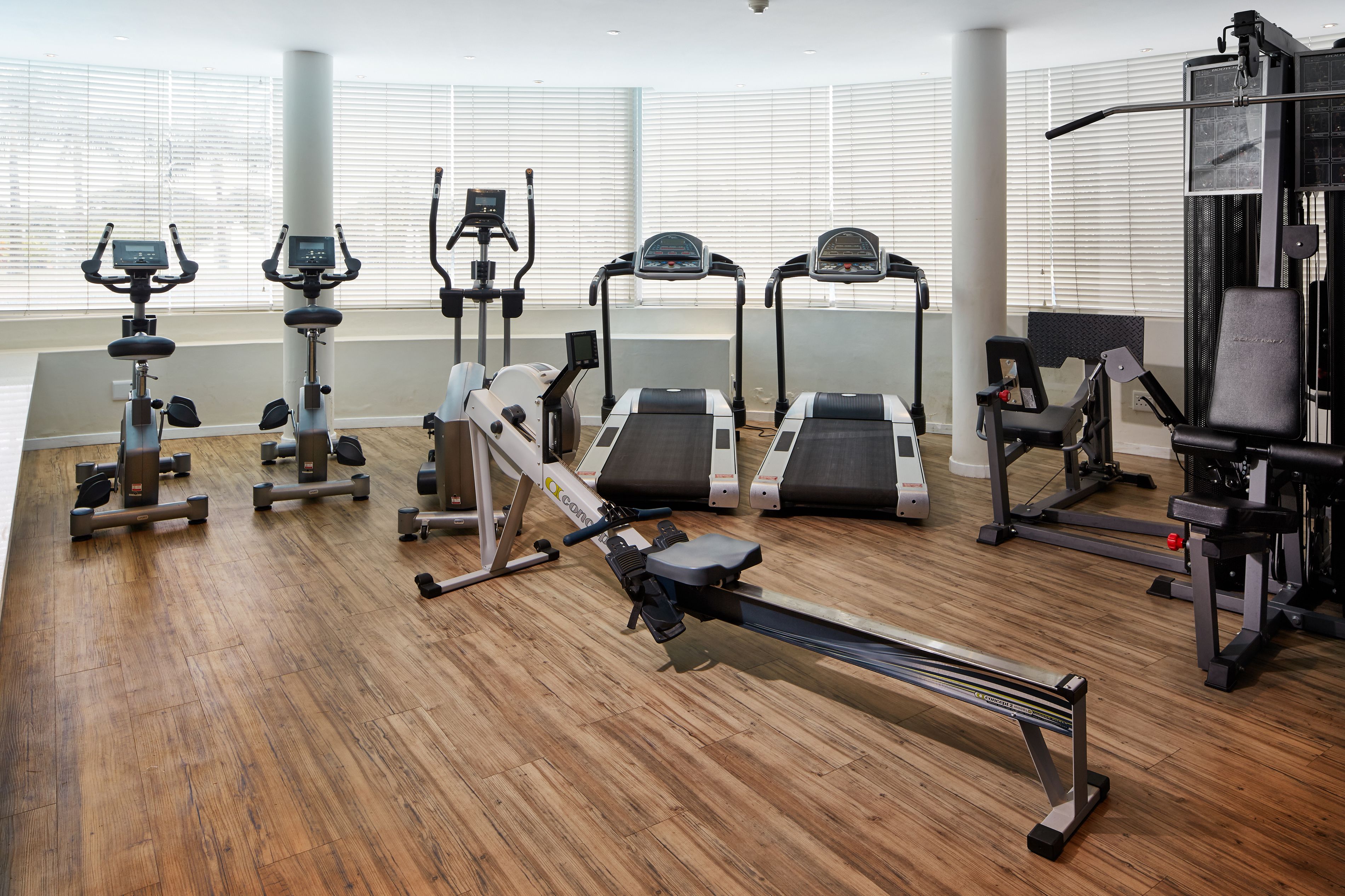 Un gimnasio con máquinas de cardio, bancos de pesas y una máquina de remo.