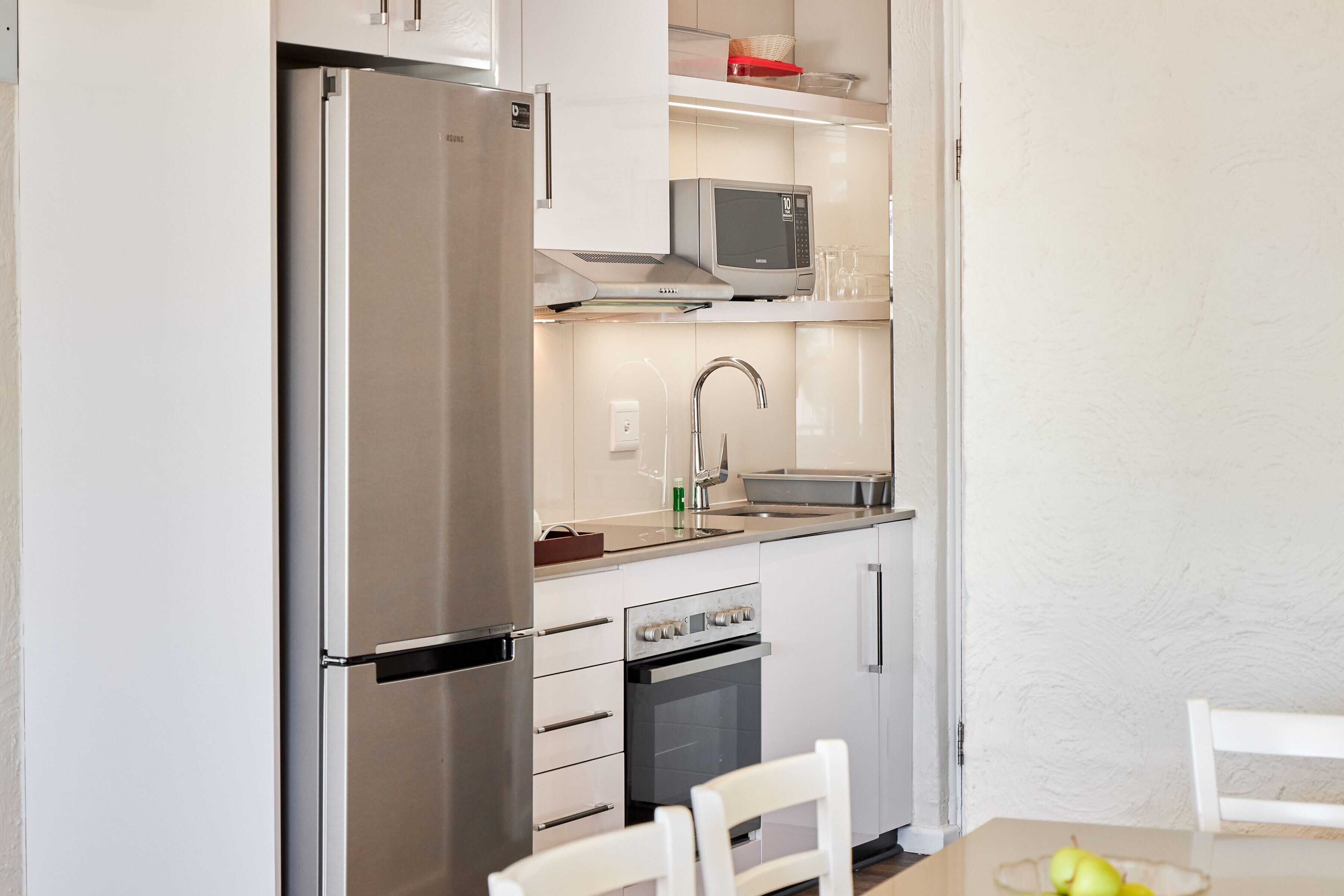 A compact kitchen with a refrigerator, microwave, oven, and sink.