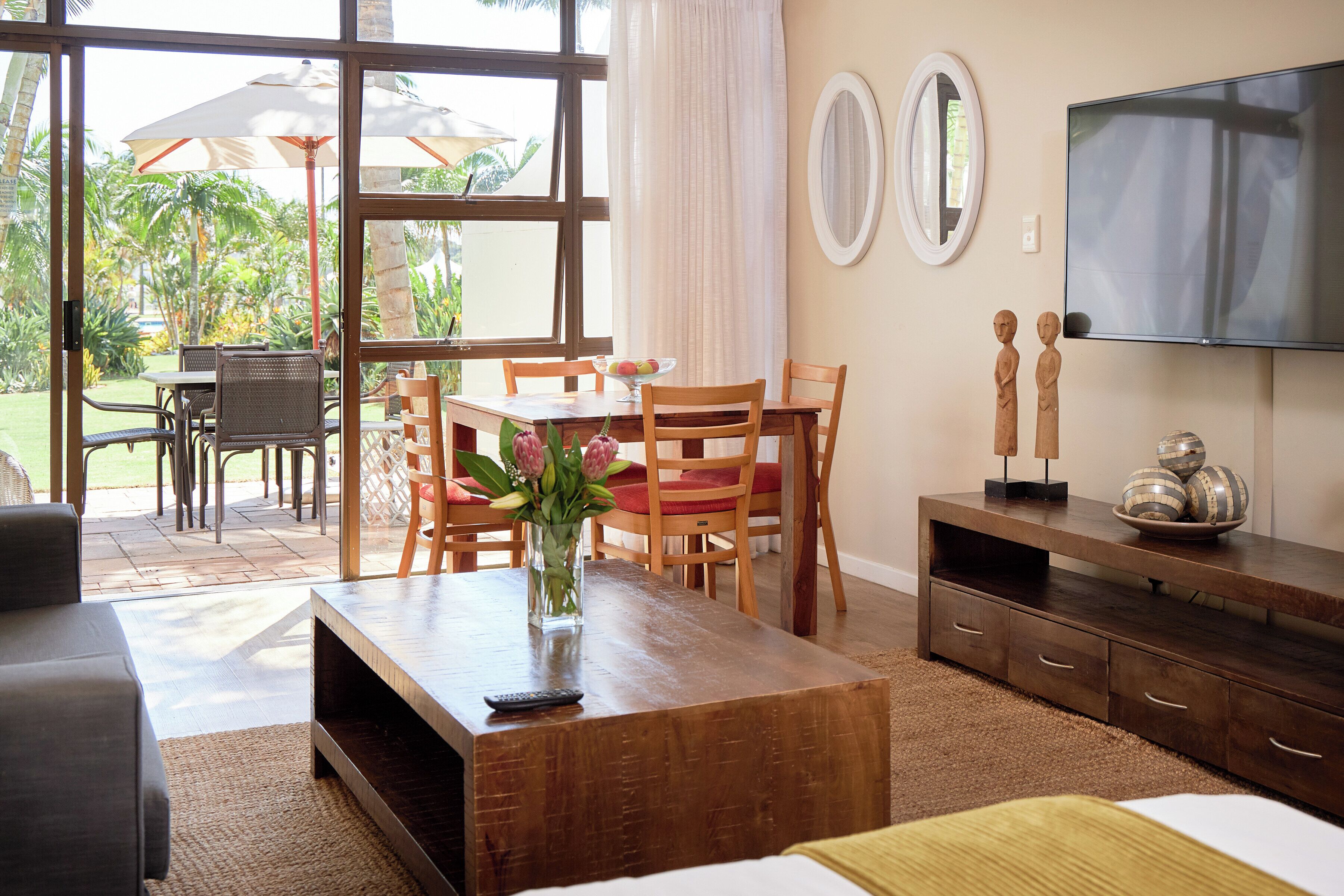 Una sala de estar bien iluminada con una mesa de centro de madera, un televisor y una zona de comedor con sillas y una mesa.