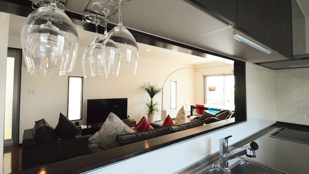 A modern kitchen with a large island, stainless steel appliances, and a flat-screen TV. - The White Reef (Uruma)