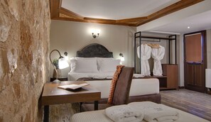 A hotel room with two beds, a wooden desk with a lamp, a chair, and a robe rack with robes. - Frontzu Politia (Ioannina)