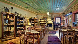 A cozy, well-lit room with wooden furniture, shelves filled with bottles, and a fireplace. - Frontzu Politia (Ioannina)