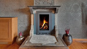 A fireplace with a stone mantel, a wooden cabinet to the left, and two vases on either side. - Frontzu Politia (Ioannina)