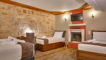 A hotel room with two beds, a stone wall, a fireplace, and a television mounted above it.
