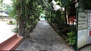 A stone pathway lined with potted plants and a signboard with pool rules and notifications. - L'Elephant Blanc Resort (Phnom Penh)