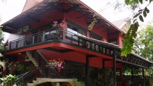 A two-story building with a red facade, a balcony with black railings, and a stone staircase leading to the entrance. - L'Elephant Blanc Resort (Phnom Penh)