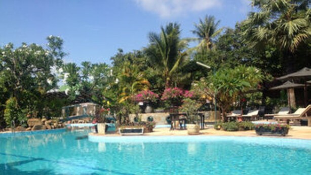 A clear blue pool surrounded by lounge chairs and palm trees. - L'Elephant Blanc Resort (Phnom Penh)