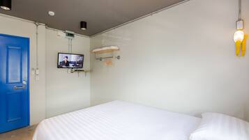 Habitación de hotel con una cama grande, una puerta azul, un televisor montado en la pared y un perchero.