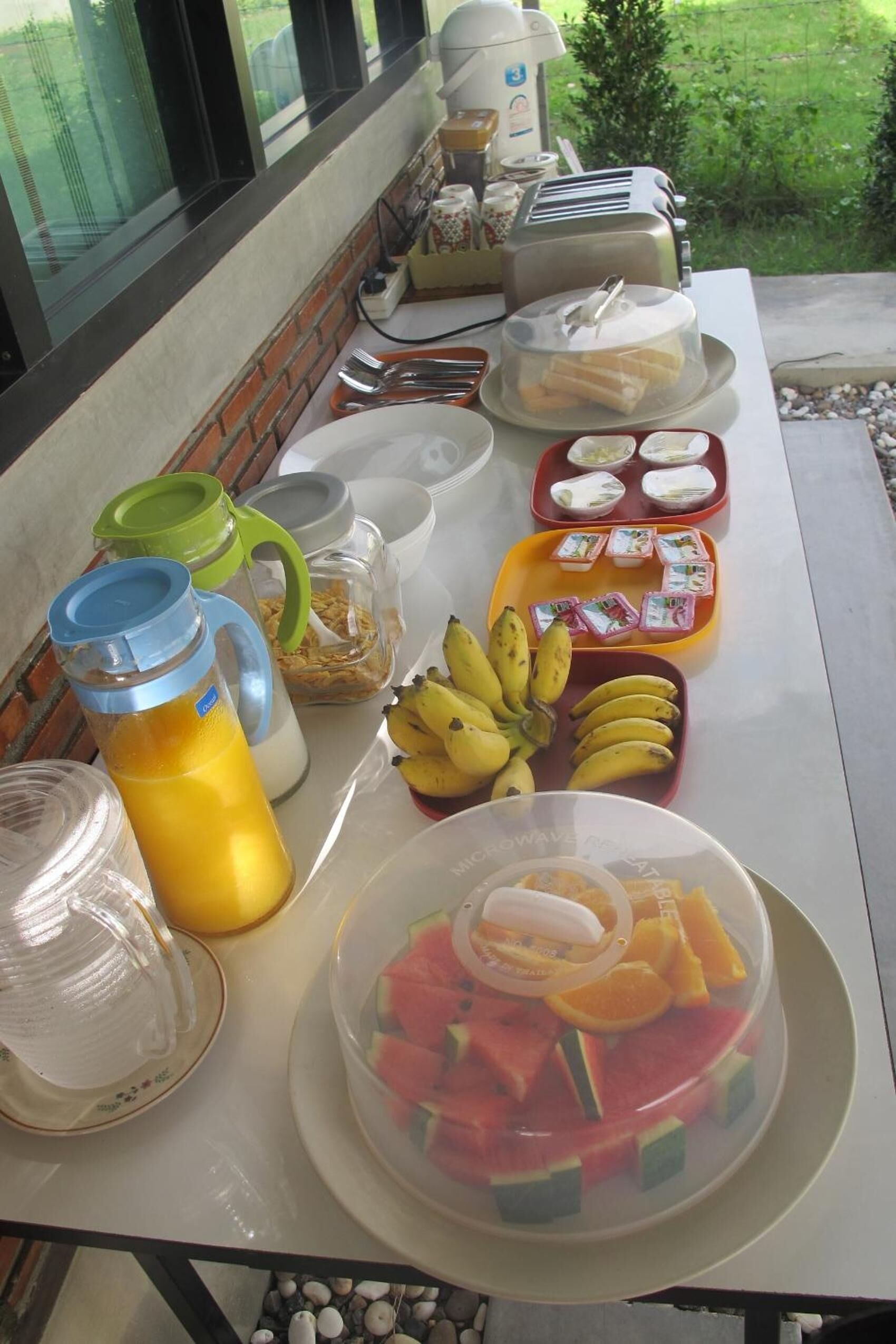 A breakfast table with various food items and a coffee maker.