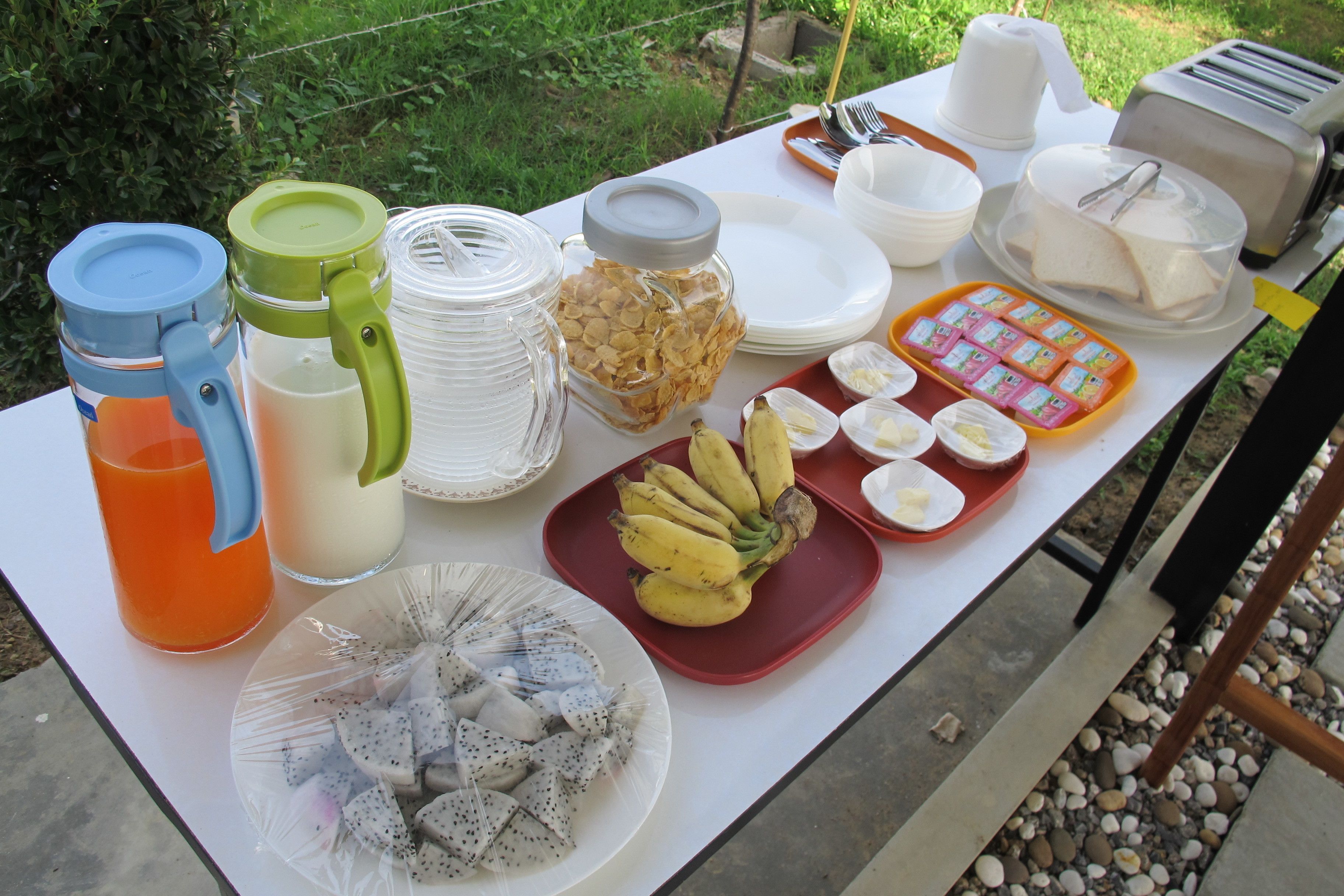 A table set with breakfast items including fruits, eggs, and beverages.
