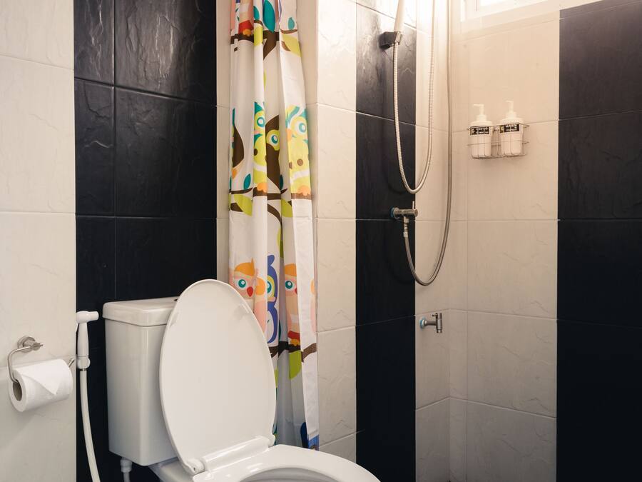 Un baño moderno con inodoro, ducha y cortina estampada con motivos animales.