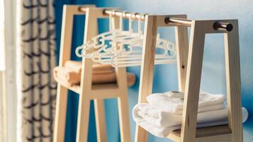 A wooden drying rack with towels and a hanging rack against a blue wall.