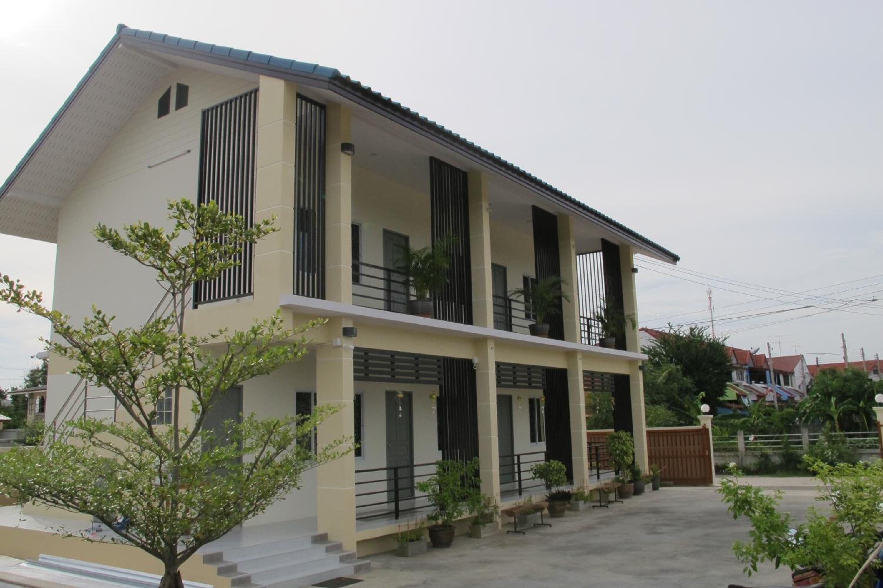 A two-story house with a balcony, potted plants, and a gated entrance.