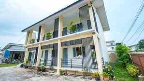 A two-story residential building with balconies, potted plants, and a concrete driveway. - Sweet Dreams Guest House (Phetchaburi)