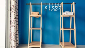 A room with a blue wall, a wooden shelf unit with towels, and a patterned curtain. - Sweet Dreams Guest House (Phetchaburi)