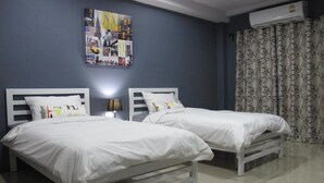 A hotel room with two white beds, a wall-mounted air conditioner, and a patterned curtain. - Sweet Dreams Guest House (Phetchaburi)