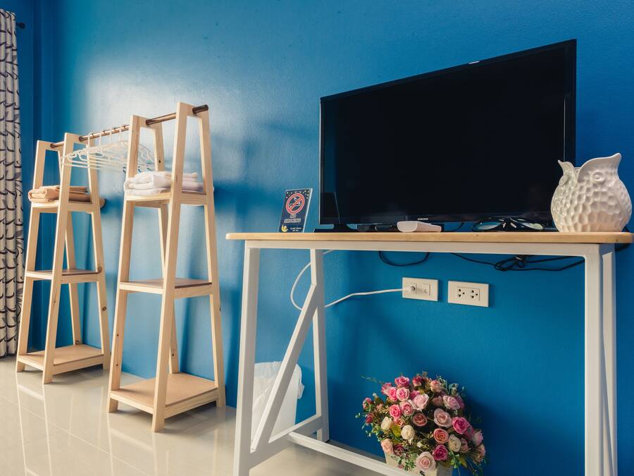 Ein Zimmer mit blauer Wand, einem Fernseher auf einem Holzboden, einer weißen Vase und einer Holzkonsolenwand.