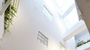 A multi-level interior with a central open space, multiple doors, and a skylight. - OwlStay Flip Flop Hostel Garden (Taipei)