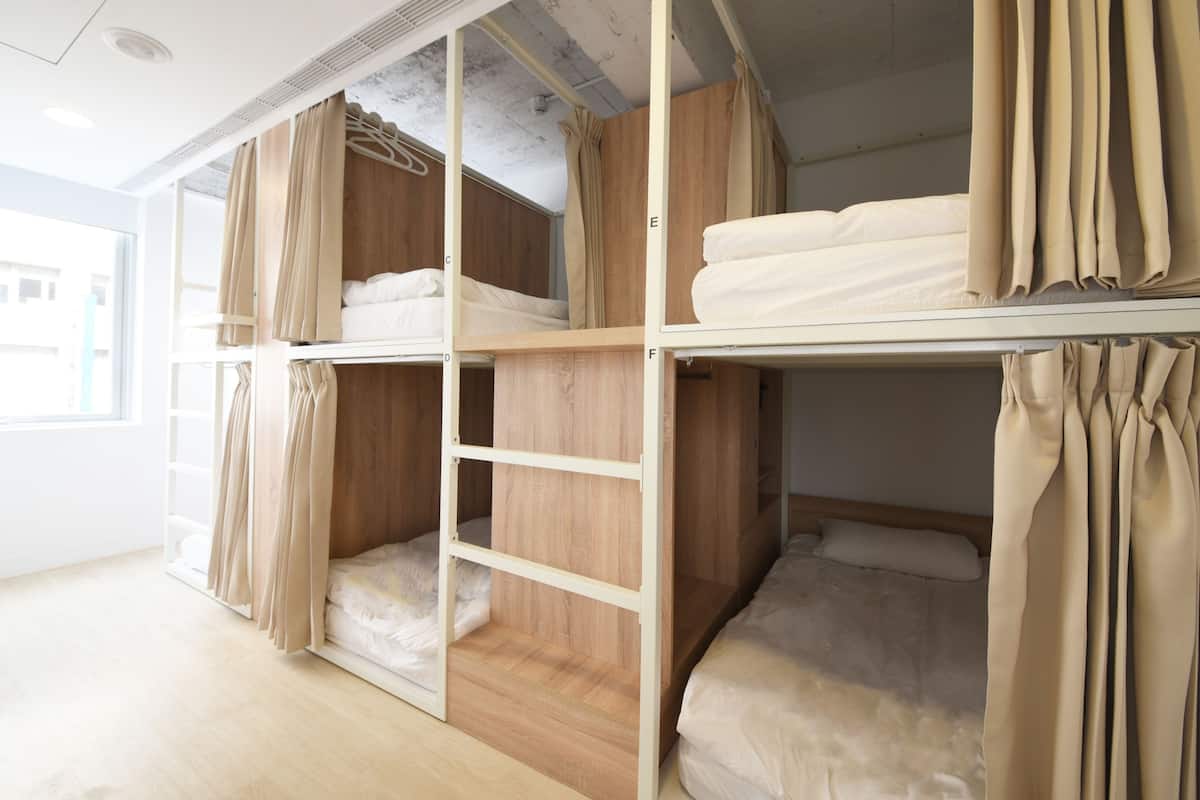 Une chambre avec un lit superposé, dont la structure est en bois et qui est agrémentée de rideaux beiges.