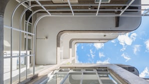 A high vantage point of a building's interior, featuring a large window with a clear sky view, metal railings, and a concrete floor. - OwlStay Flip Flop Hostel Garden (Taipei)