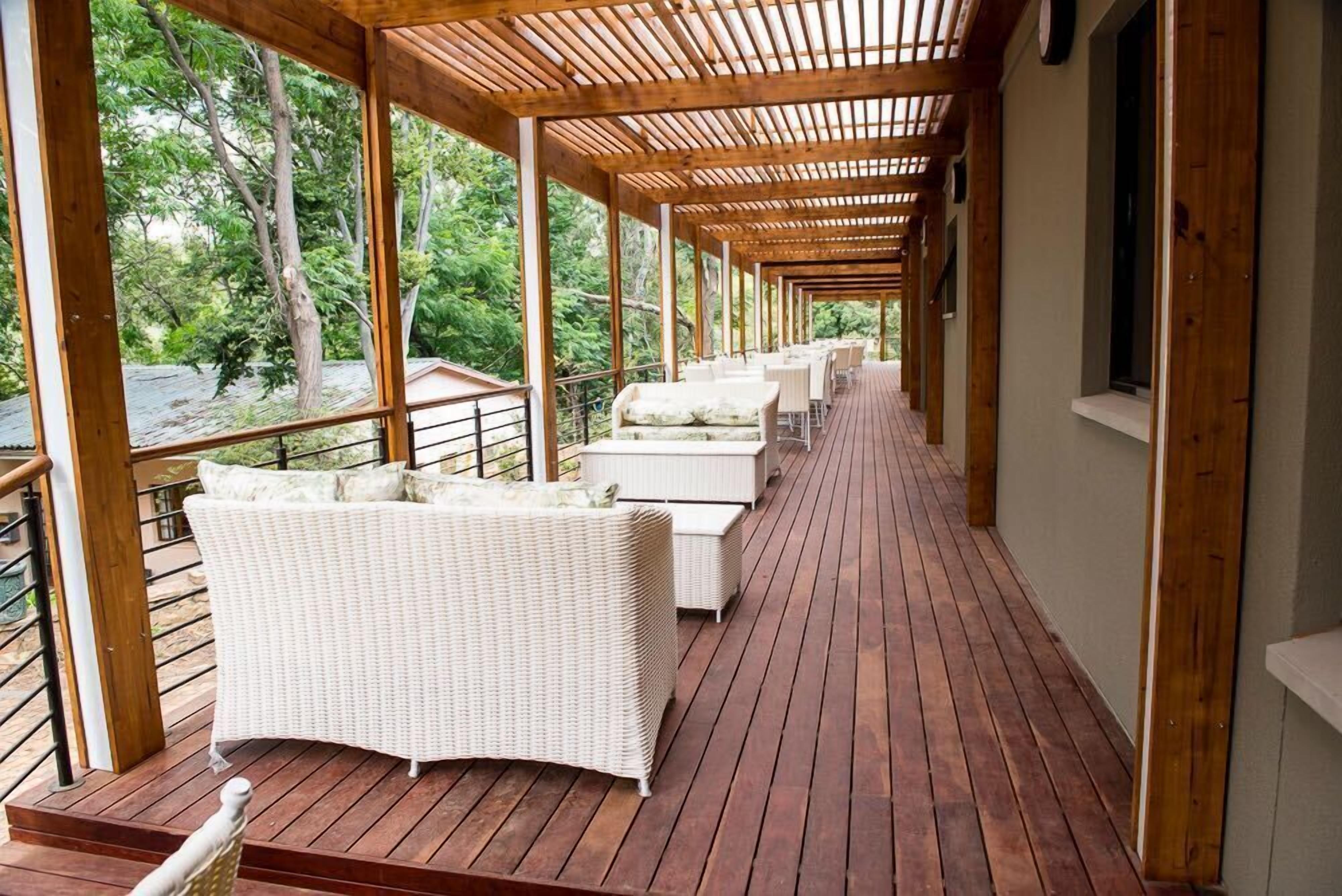 A covered outdoor seating area with wicker furniture and wooden flooring.