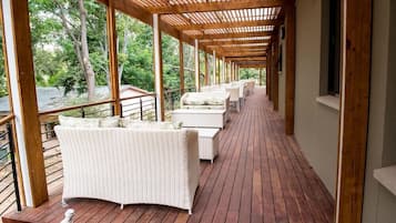 A covered outdoor seating area with wicker furniture and wooden flooring.