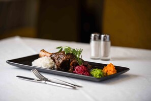 A plate of food with white rice, a meat dish, and a side of vegetables on a black plate.
