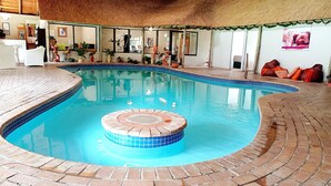 An indoor swimming pool with a central hot tub, surrounded by a brick deck and a tiled edge. - Sparkling Waters Hotel & Spa (Rustenburg)