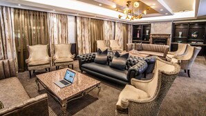 A luxurious living room with a fireplace, leather sofas, and a laptop on a coffee table. - Sparkling Waters Hotel & Spa (Rustenburg)