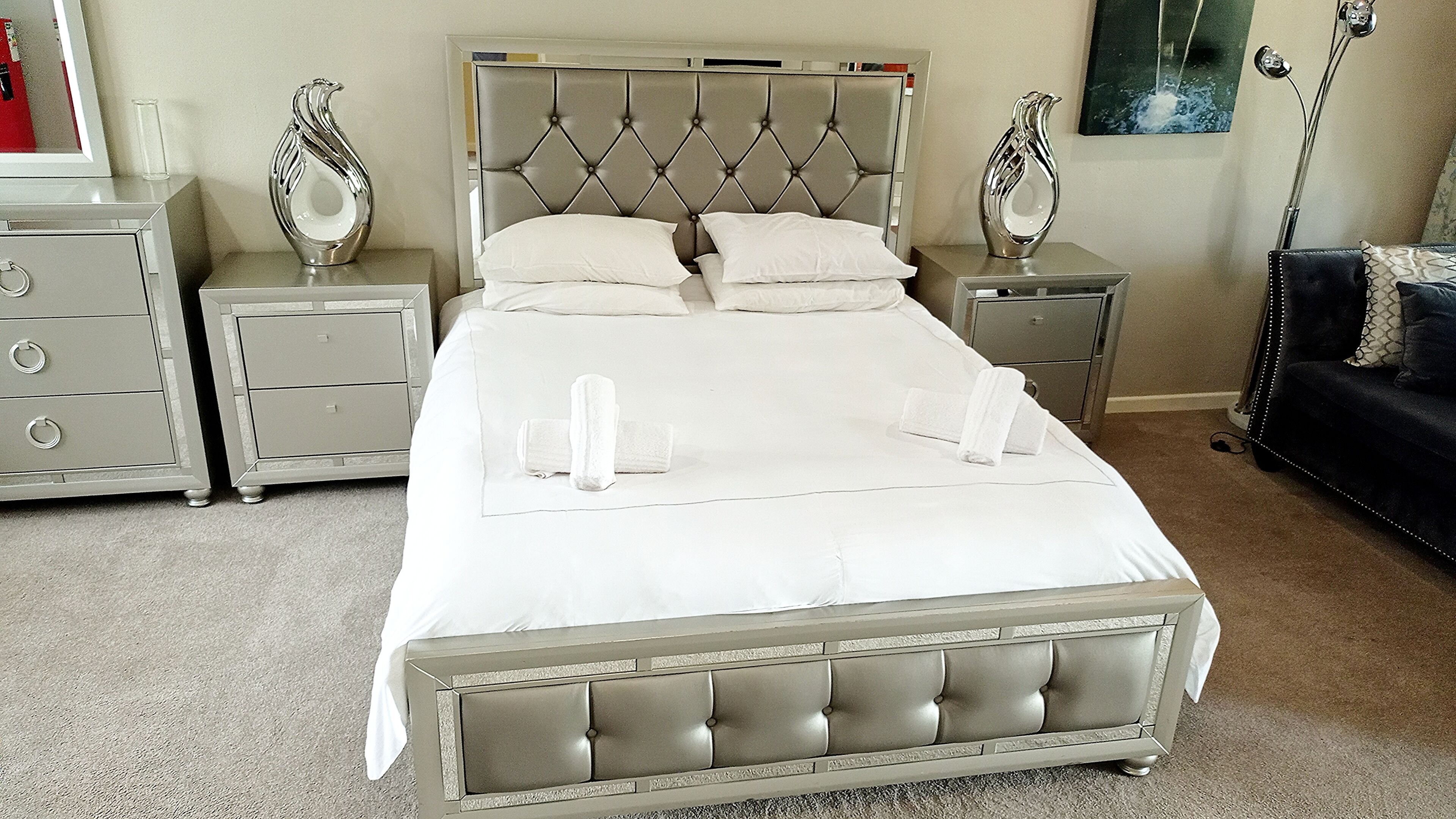 A neatly made bed with white linens and two decorative vases on nightstands.