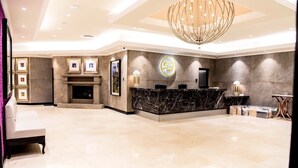 A spacious lobby with a marble reception desk, a fireplace, framed artwork, and a chandelier. - Sparkling Waters Hotel & Spa (Rustenburg)