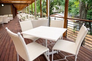 An outdoor patio with white wicker furniture, including a table and chairs, set on a wooden deck. - Sparkling Waters Hotel & Spa (Rustenburg)