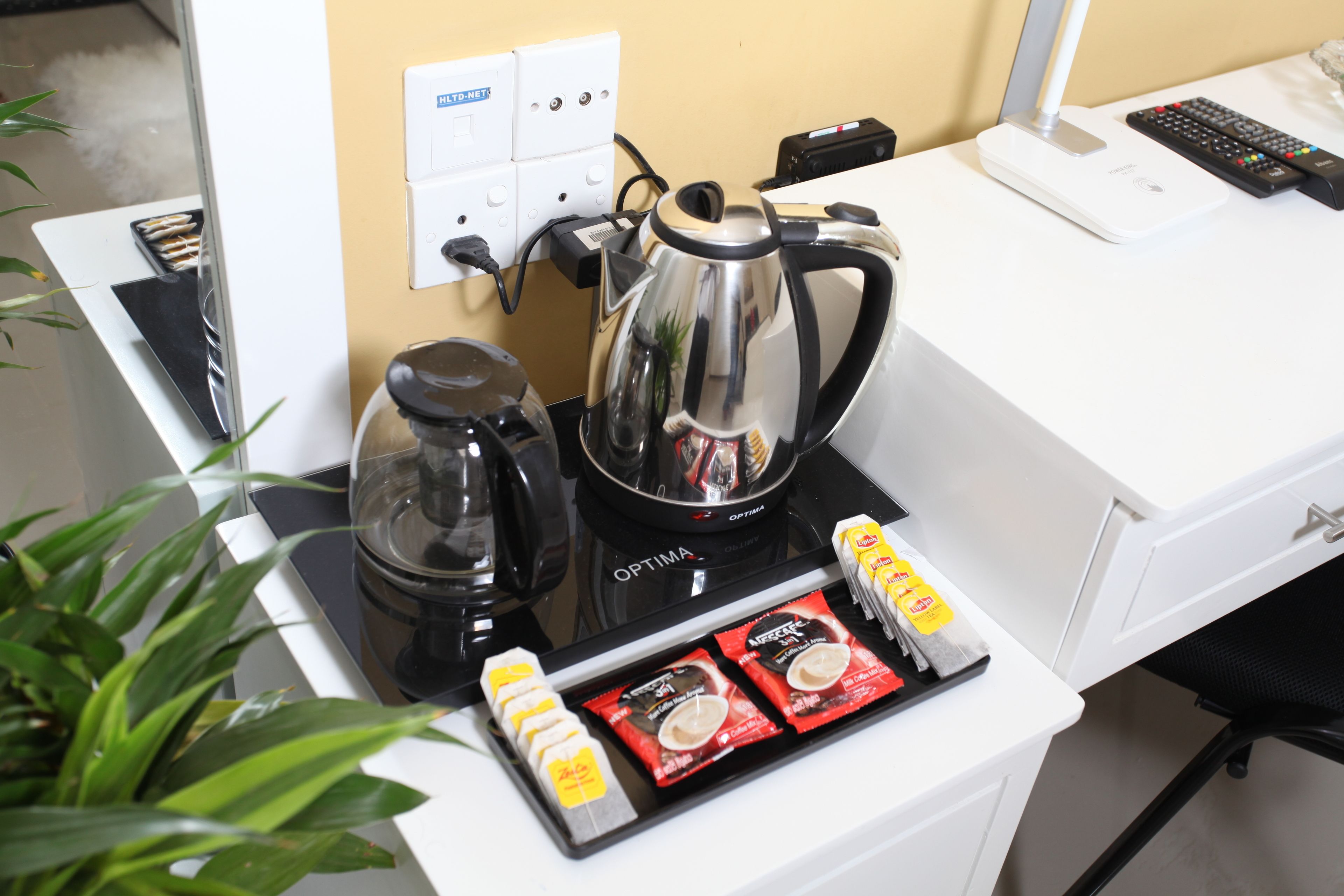 A kitchenette with a coffee maker, kettle, and packaged food items.