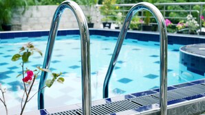 Une piscine dotée de rampes métalliques et d’un bord carrelé.