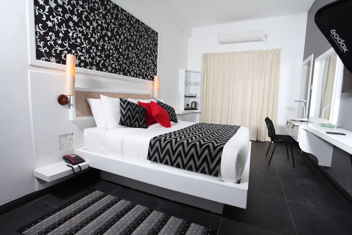 Une chambre d’hôtel moderne équipée d’un lit, d’une table de chevet, d’une lampe et d’un bureau avec une chaise.