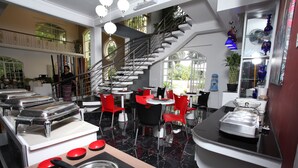 Une cuisine moderne dotée d’un îlot central, de chaises rouges et d’un escalier menant à un niveau supérieur.