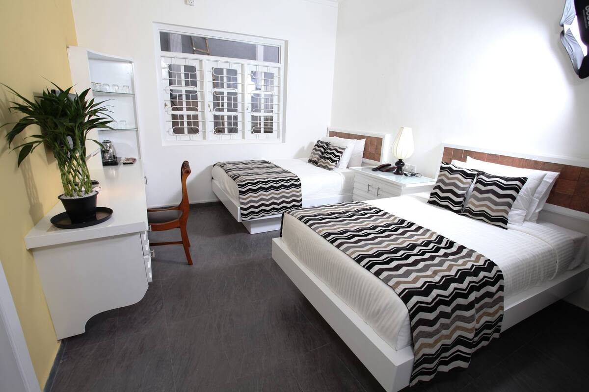 Une chambre d’hôtel avec un lit, une chaise, un bureau, une lampe et une fenêtre.