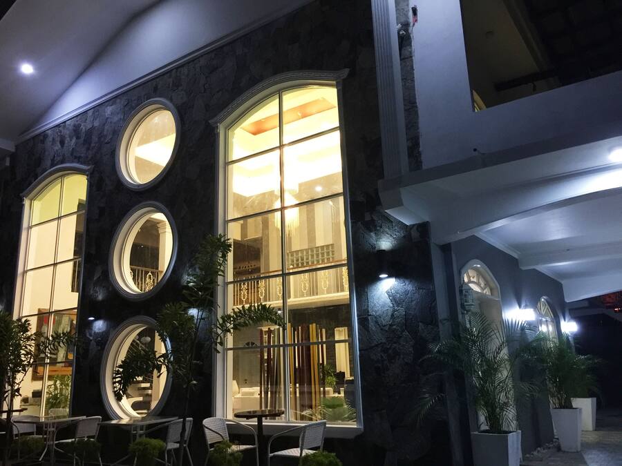 Un edificio con grandes ventanales, asientos exteriores y plantas en macetas.