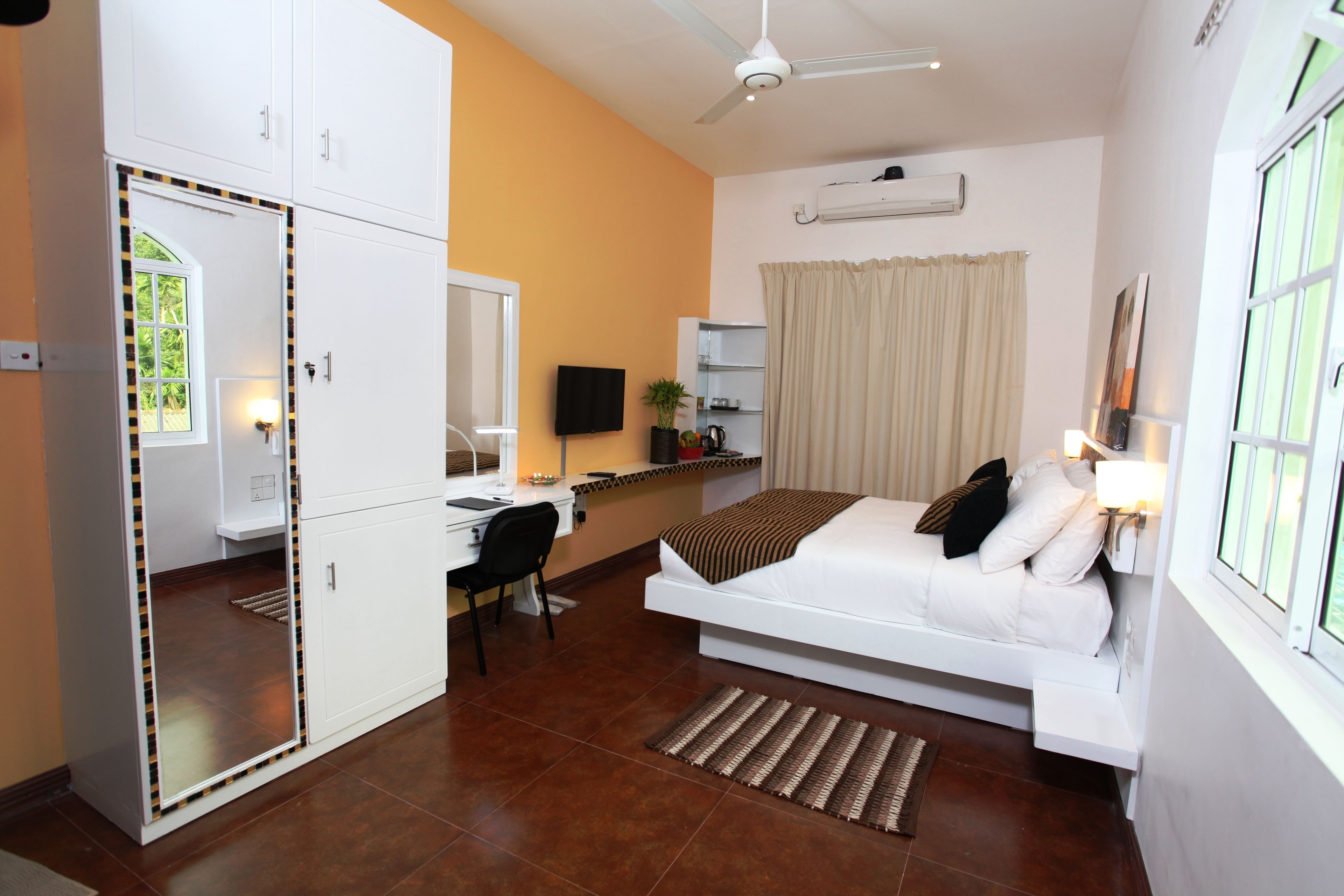 Quarto com cama, escrivaninha, cadeira e espelho.