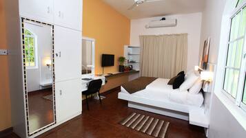 Quarto com cama, escrivaninha, cadeira e espelho.