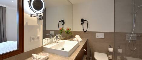 A modern bathroom with a large mirror, a sink, a toilet, and a shower.