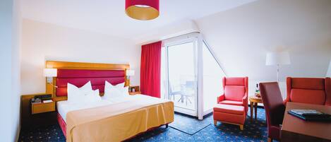 A hotel room with a bed, a desk, a chair, and a large window.