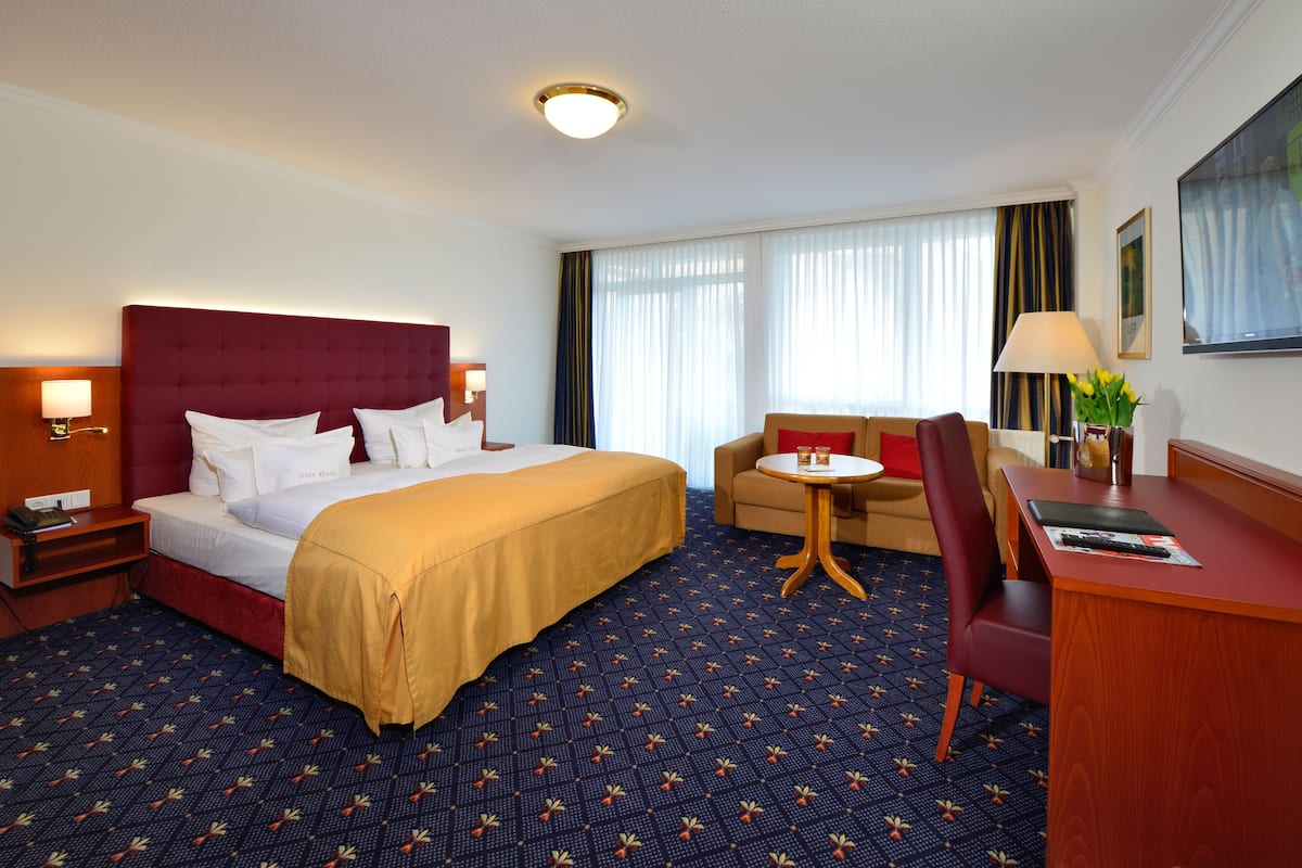 Quarto de hotel com uma cama grande, uma mesa, uma cadeira e um sofá.