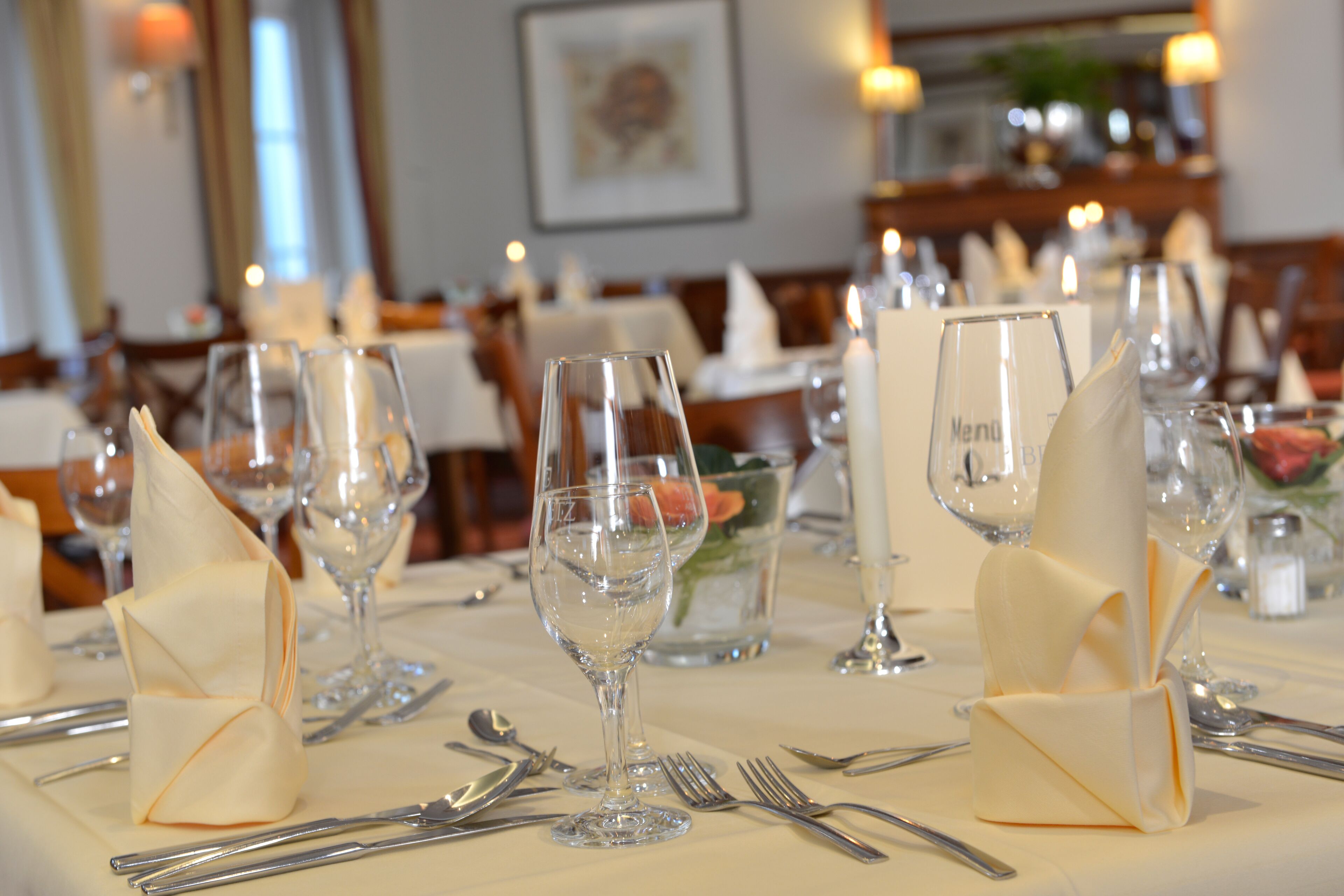 A dining table set with multiple wine glasses, forks, and knives.