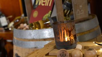 Una candela in un portacandela su una superficie di legno, con botti e un cartello sullo sfondo.