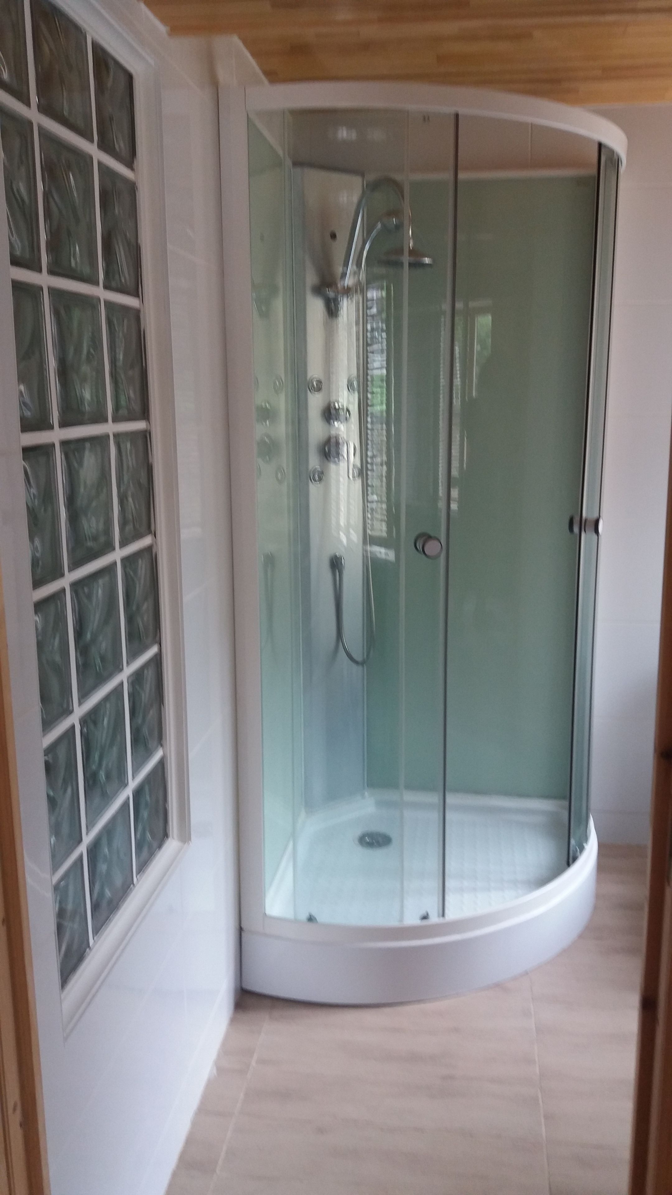 A glass-enclosed shower room with a curved design, a showerhead, and a control panel.
