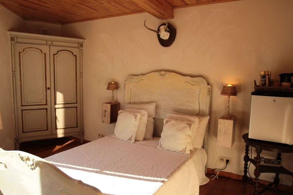 Un dormitorio con cama, lámparas de noche, cómoda y reloj de pared.